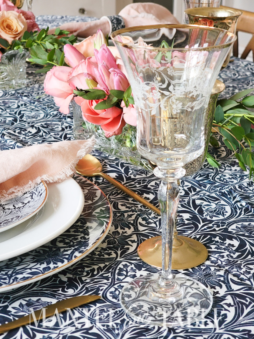Engraved crystal wine glass with gold rim on a formal table