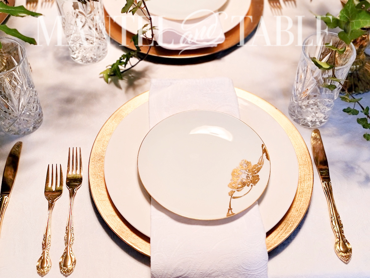 White and gold place setting closeup with gold flatware
