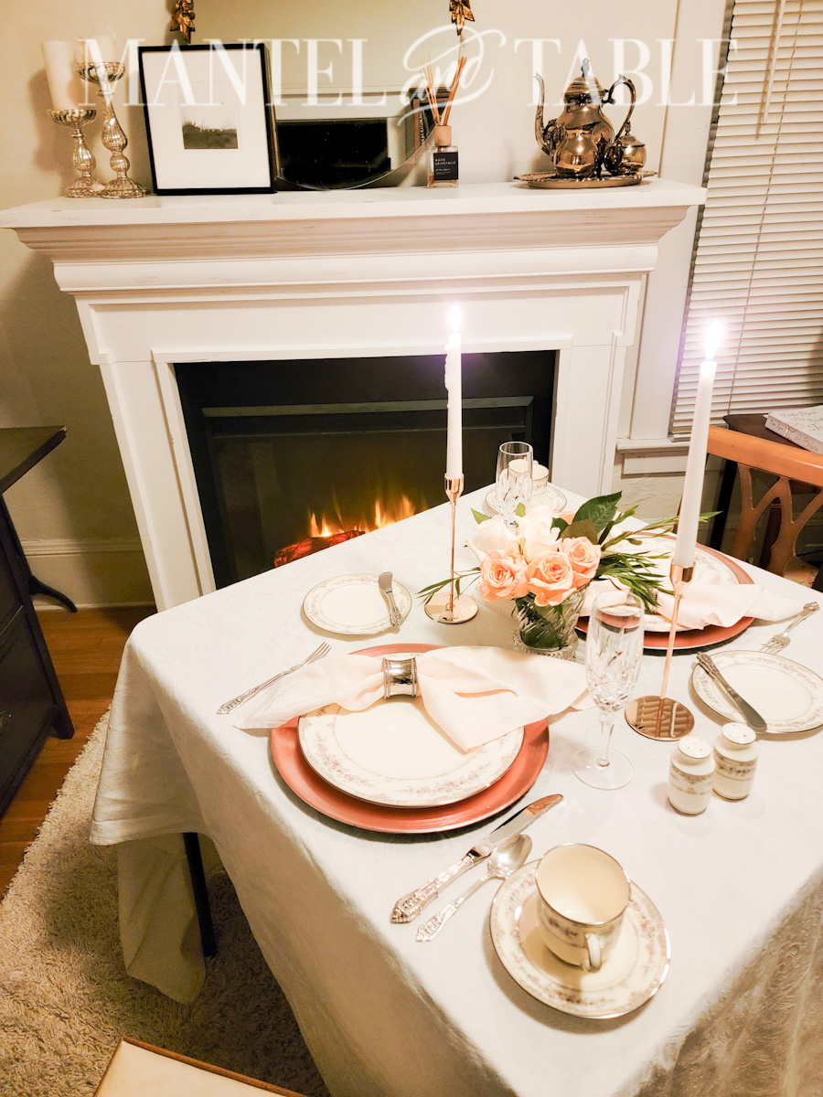 White fireplace with mantel, elegant breakfast Table for two in front.