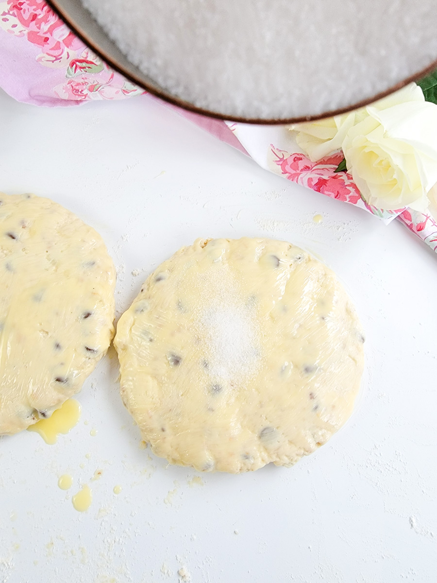 Sprinkling sugar over cream scone dough rounds