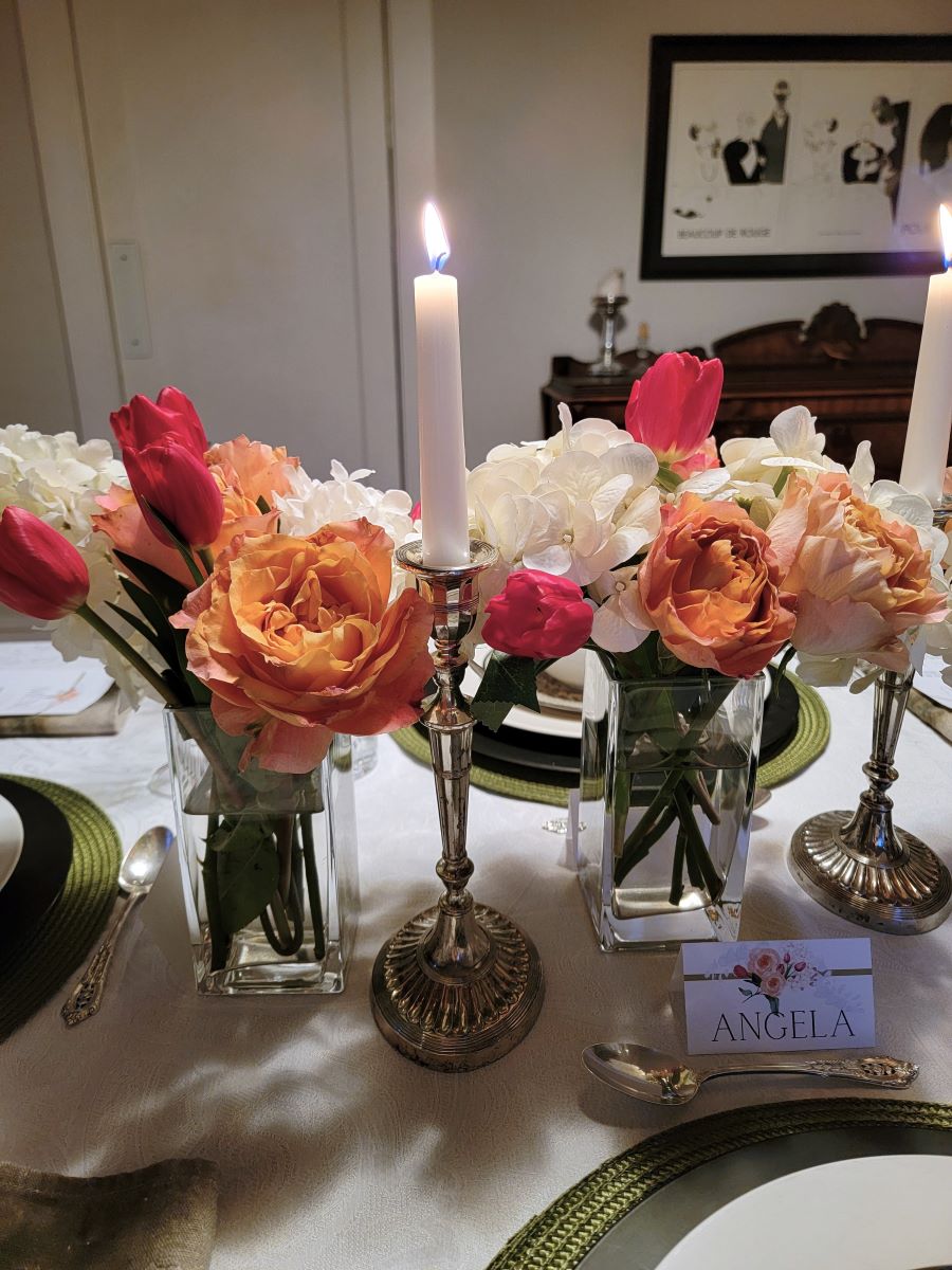 Vases of flowers lined up for the centerpiece, silver taper candle holders