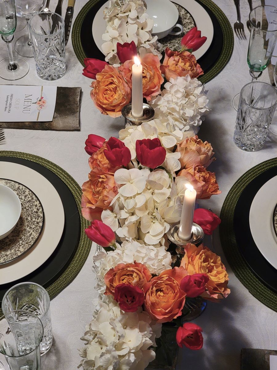 Closeup of flower centerpiece with red tulips, peach roses, and white hydrangeas