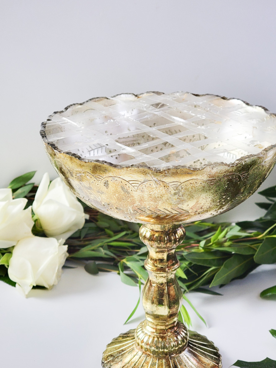 Closeup of tape grid on top of a gold pedestal vase
