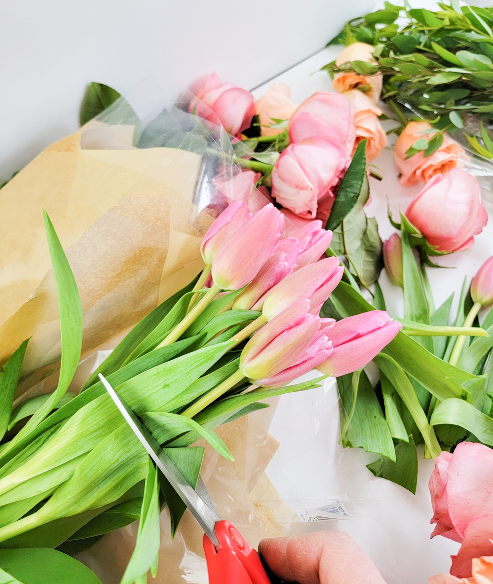 Scissors trimming a bunch of pink tulips