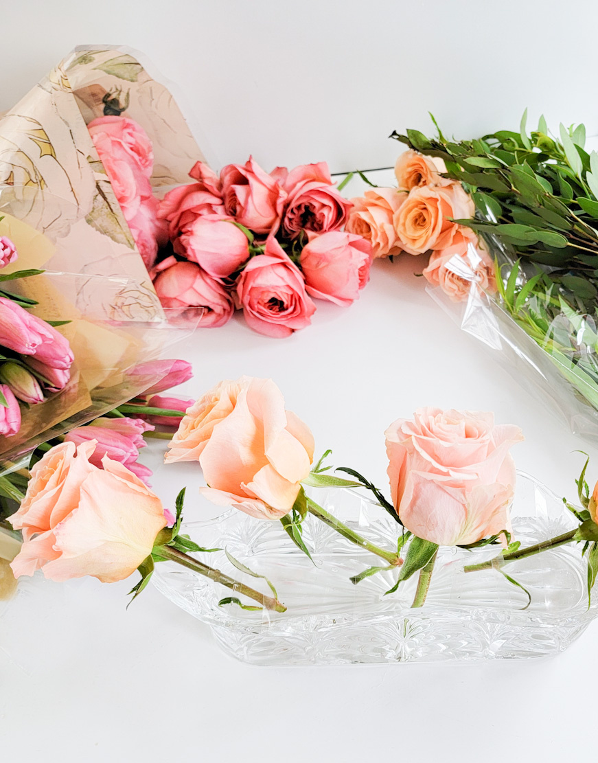 Short peach roses in vase with tape grid on top