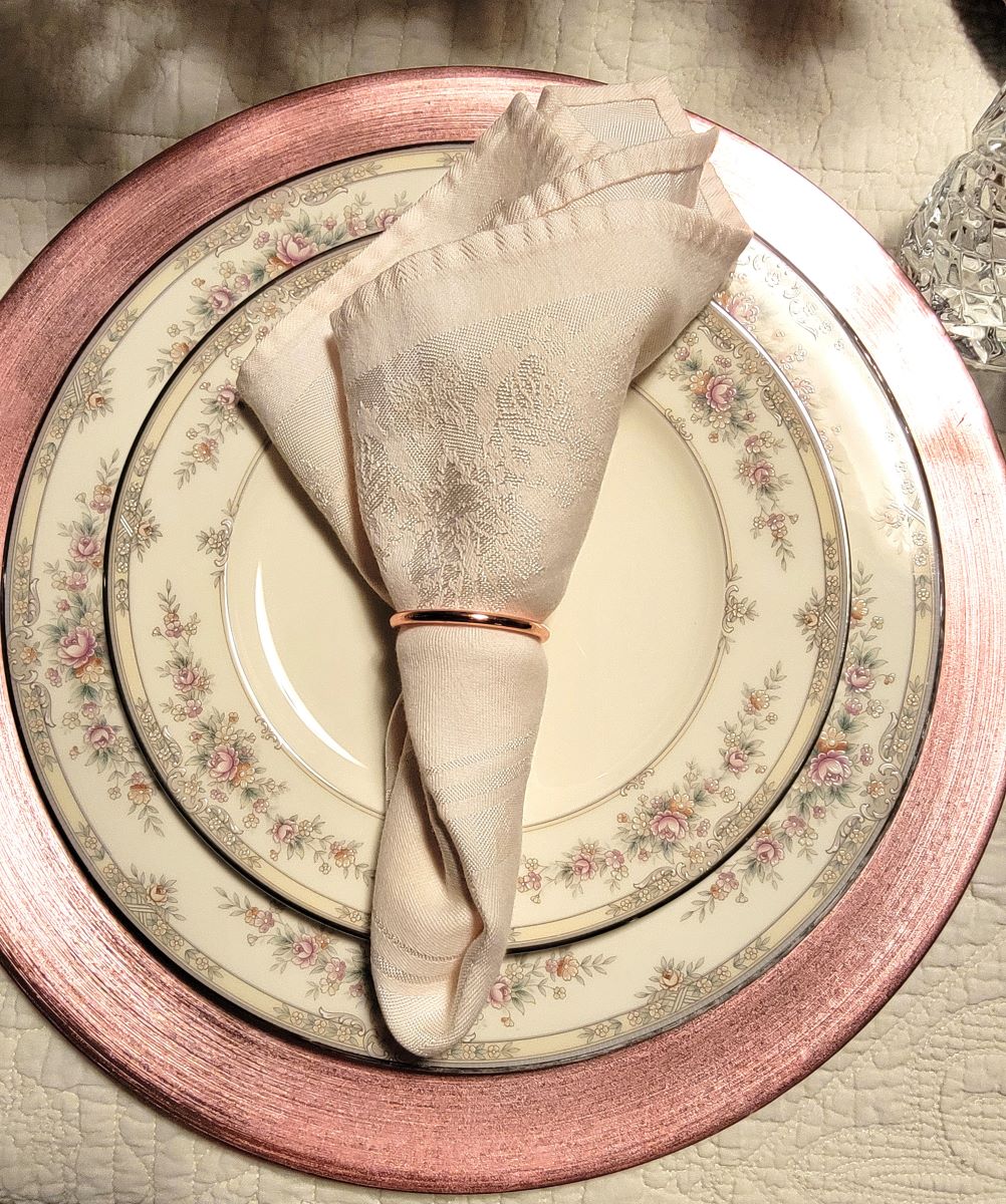 top view of pink flowered china plates in formal place setting