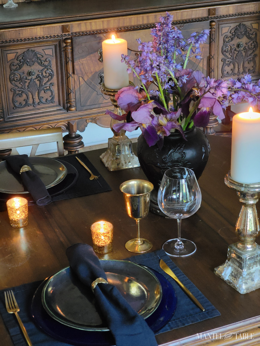 Formal table showing two place settings, flower arrangement, and pillar candle holders