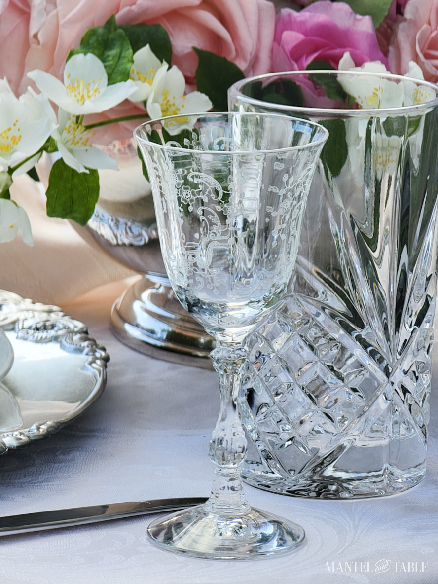 Cut crystal water glass and etched vintage cordial glass in a table setting