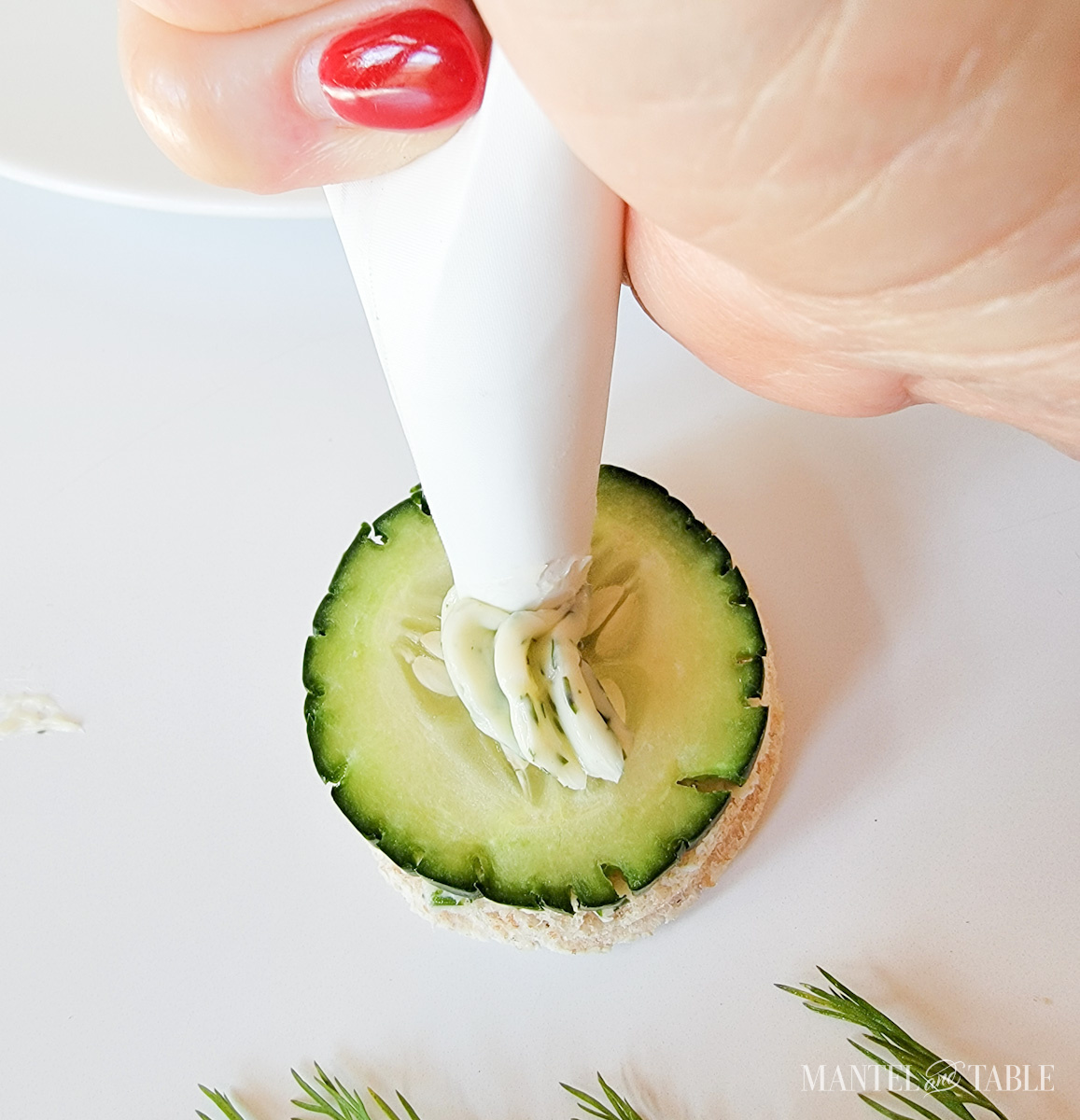 Squeezing dill butter from a pastry bag onto easy cucumber sandwiches