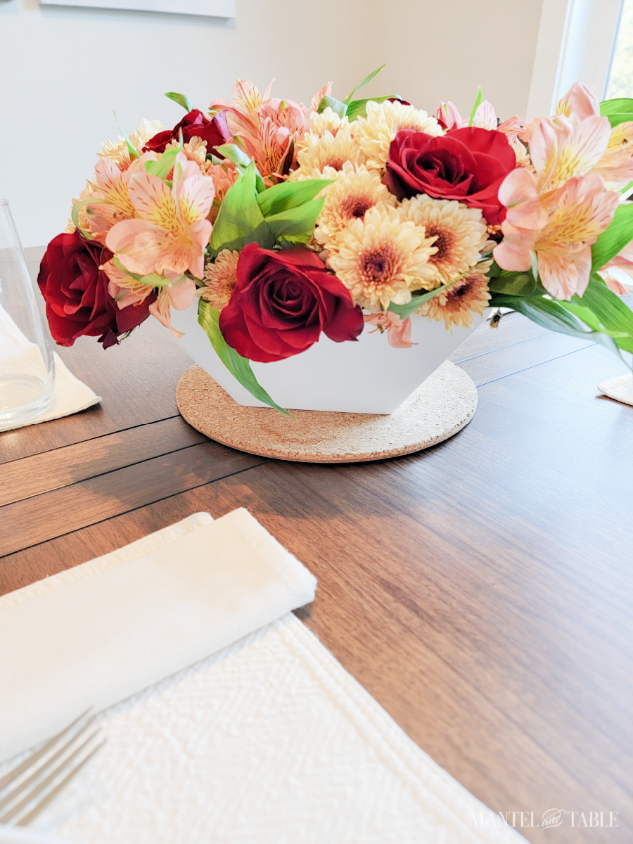 Flower arrangement of red roses, yellow mums, and peach alstroemeria in a white bowl