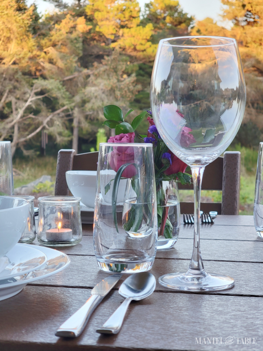 Tall wine glass on a formal table with the sun on trees in the background